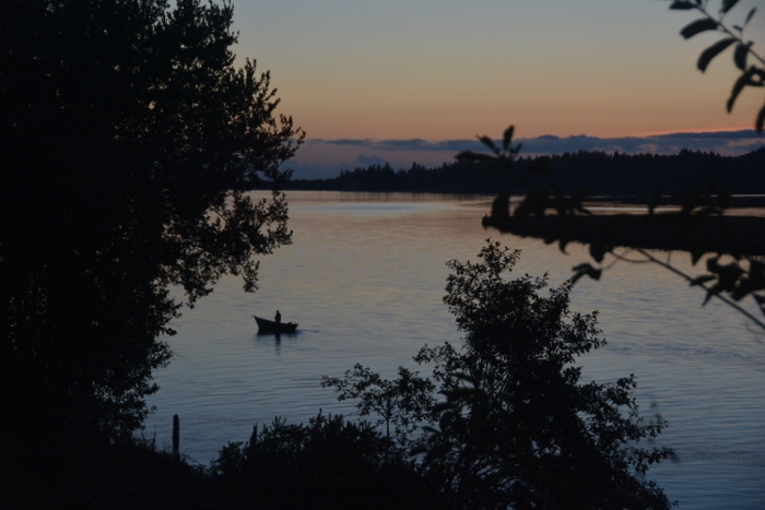 fisherman in boat silhouetted against the water 